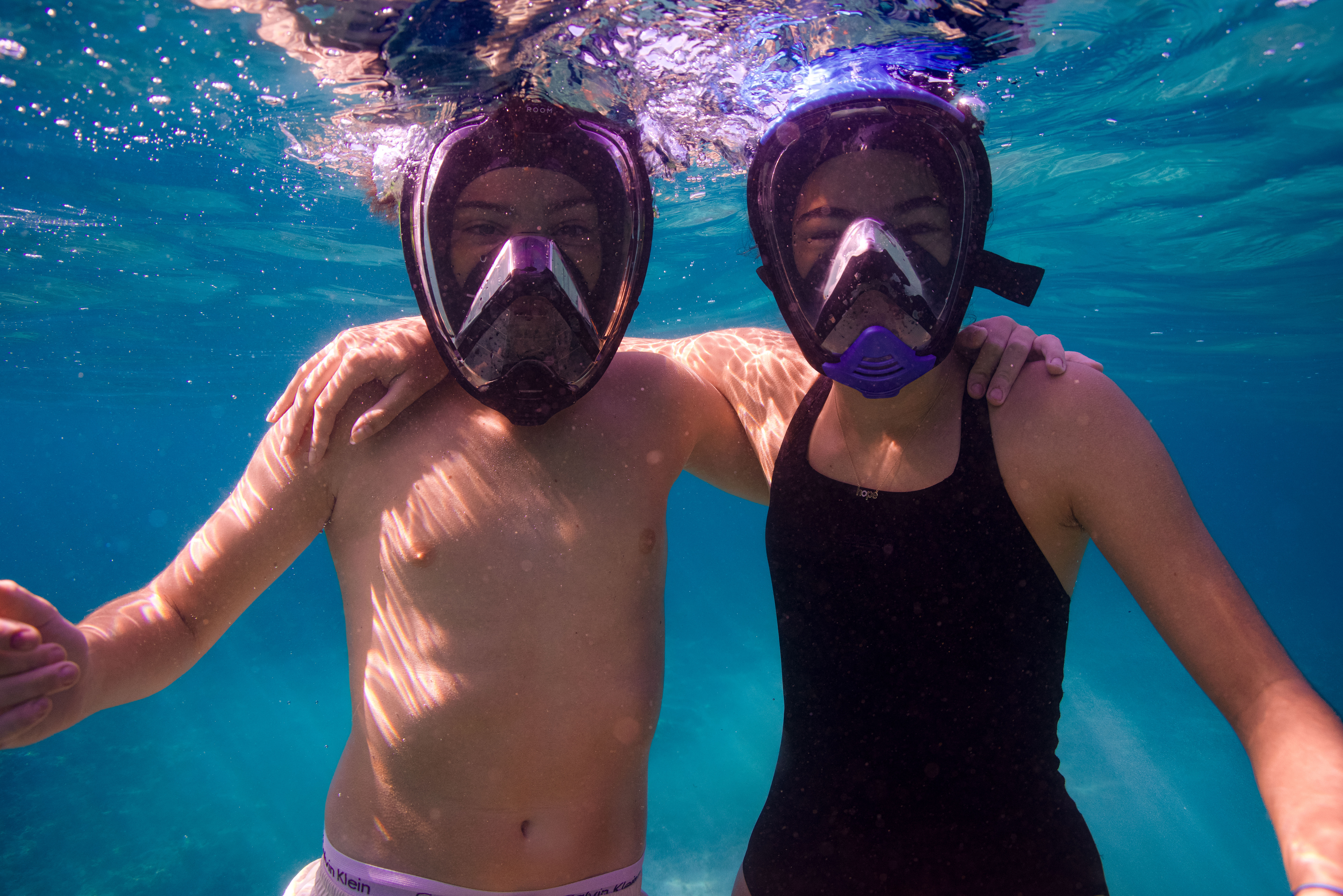 Underwater photograph of two snorkelers with full-face masks in clear blue water in Dibba Fujairah